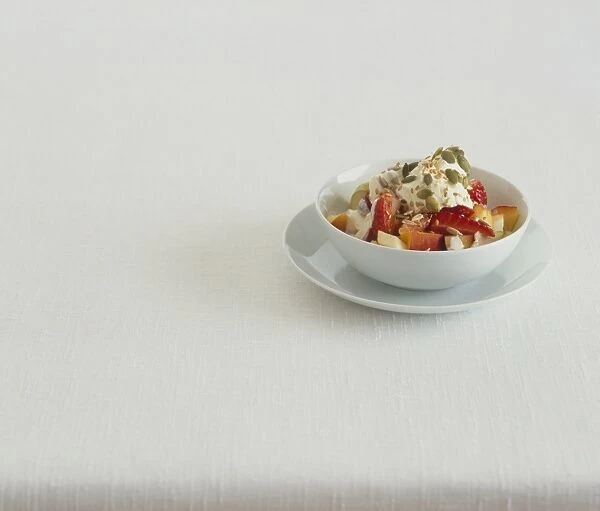Fruit and nuts with natural yoghurt served in white bowl on plate