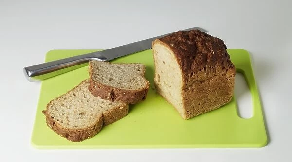 Gluten-free bread with a couple of slices cut off, and a bread knife, on a cutting board