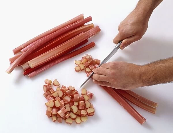 Hands chopping rhubarb stalks into small pieces, close-up, view from above