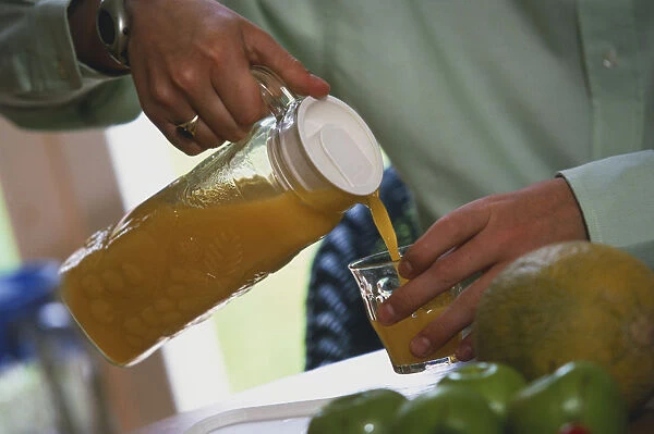 Man pouring orange juice into a glass tumbler