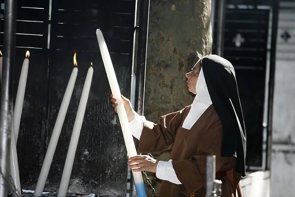Nun lighting a candle at the Lourdes shrine
