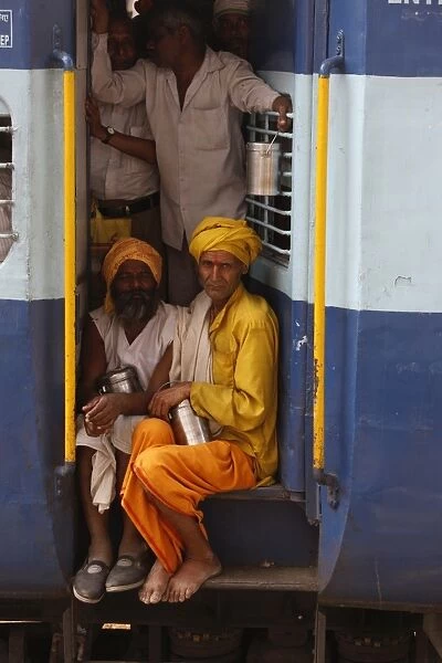 Passengers standing and sitting between railway cars
