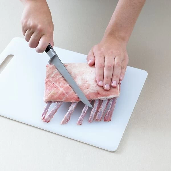 Person cutting rack of lamb, close-up