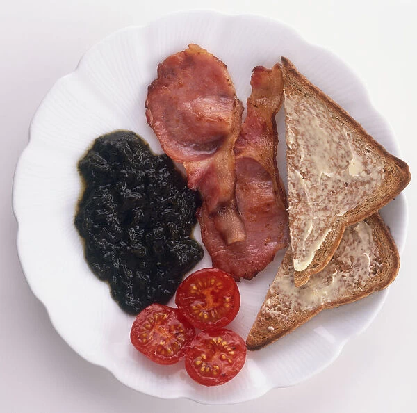 Plate of fried bacon, cherry tomatoes, slices of toast and laverbread made from seaweed, a traditional breakfast from Wales, view from above