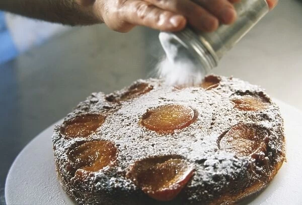 Plum cake being dusted with icing sugar
