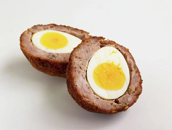 Scotch egg, sliced in two showing hard-boiled egg and sausage meat in breadcrumbs, close-up