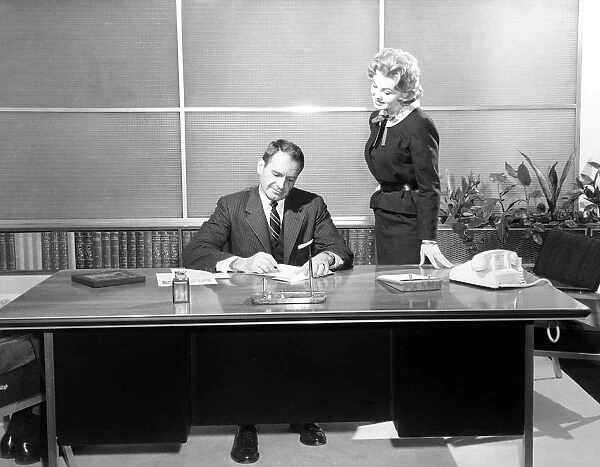 Secretary giving businessman papers to sign