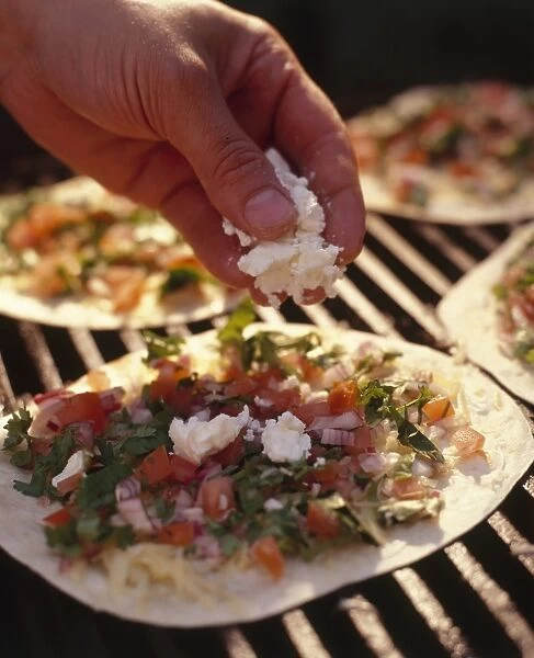 Sprinkling feta cheese over quesadillas with tomato and herb salsa