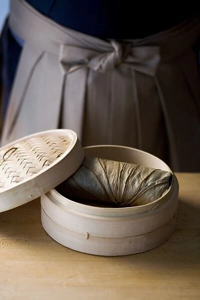 Stuffed lotus leaf in bamboo steamer basket with lid on the side, close-up