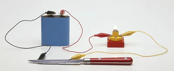 Testing for conductivity using a battery connected by a lead to a small light bulb, a lead leading from the battery to a knife and a lead from the bulb to the knife