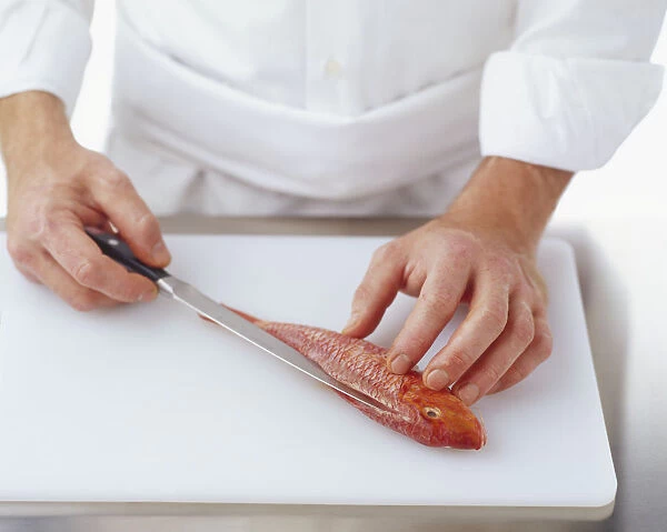 Using a knife to cut a red mullet down the length of the back