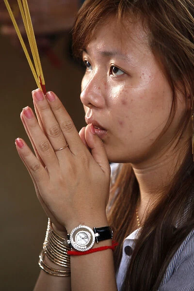 Young woman praying with incense sticks