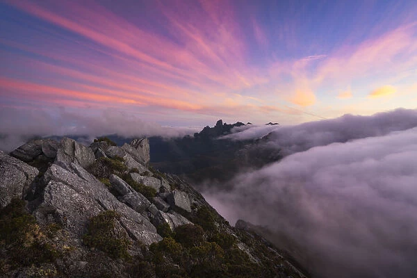 Sunset and fog flow over Federation Peak and the Eastern Arthur Range from the summit of