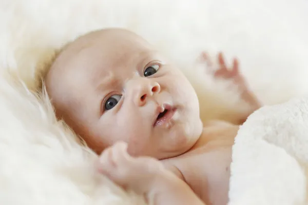 Baby girl, 3 months, lying on a sheepskin