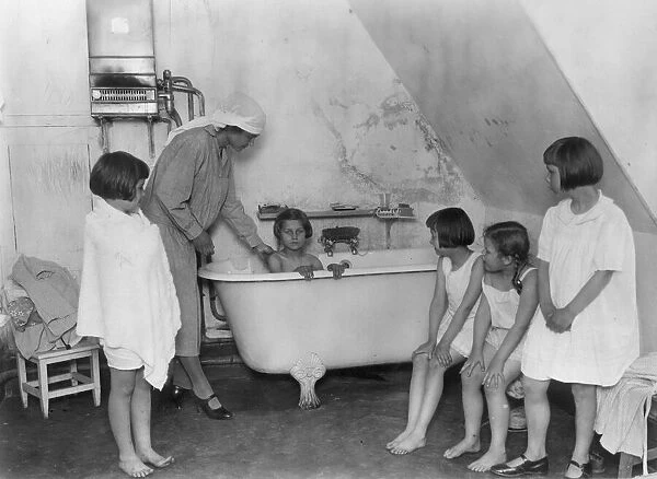 Bath Time. circa 1930: Bath time for a group of young girls
