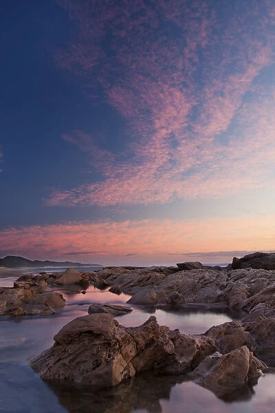 Beautiful soft colour sunrise over the sea with rocks in the foreground - Cape Vidal South Africa