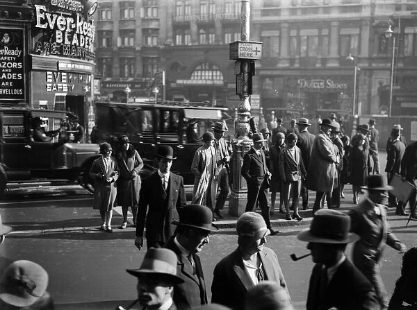 Cross Now. 1930: Pedestrians waiting to cross the road in Piccadilly Circus, London