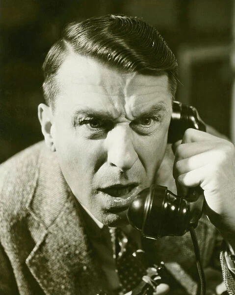 Distressed man on landline phone, (B&W), close-up