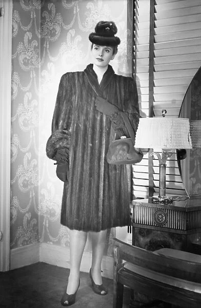Fashionable woman in mink coat and hat standing in anteroom, (B&W), portrait