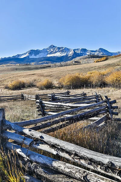 Fence along field and snow-capped San Juan Mountains, Ridgway, Colorado, USA