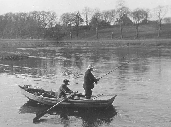 Fishing. circa 1910: Two men in a boat fishing on the River Tweed in the Scottish borders