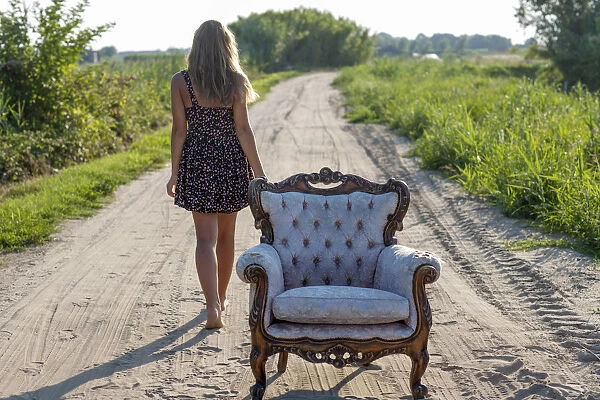 Girl, 14 years, walking along a track, an old armchair in front