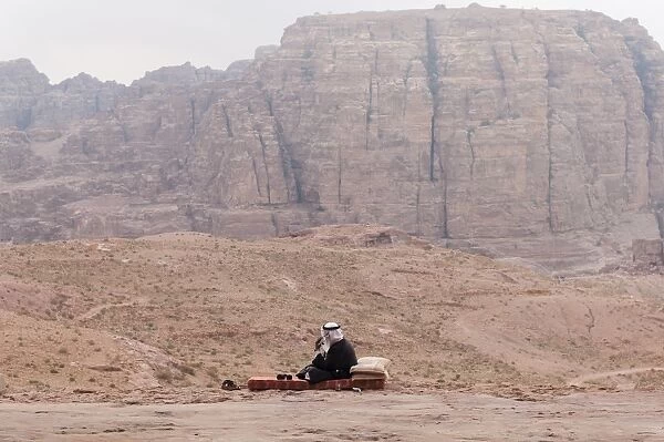 A guard in traditional attire and the splendid view of Wadi Musa from the Urn Tomb, Petra, Jordan