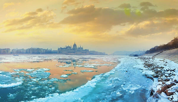 The icy Danube river and the Parliament of Hungary in Budapest at dawn in the winter