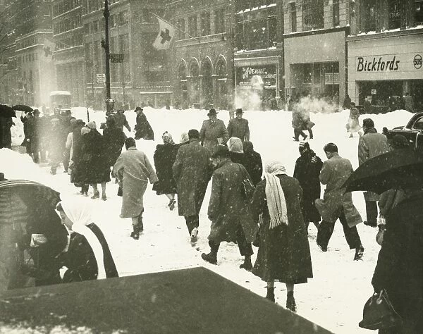 People walking on city street in blizzard, (Rear view)