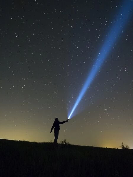 Person lighting the sky with a flashlight