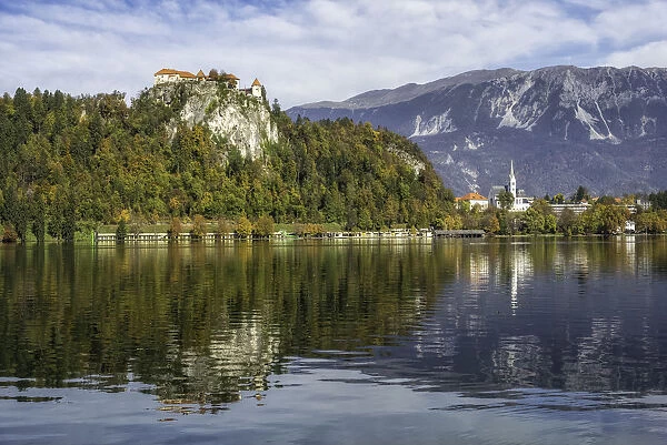 Reflection of Bled Castle overlook Lake Bled, surrounded with high mountains of the