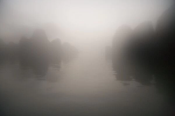 Rocks and water through mist at dawn
