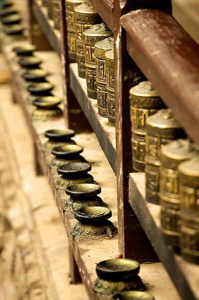A row of prayer mills and butter lamps in the Golden Temple, a Buddhist temple, Patan, Nepal, Asia