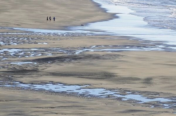 White Cliffs Beach at low tide, three men walking in the distance, rocks in the surf, Ahititi, Taranaki, North Island, New Zealand