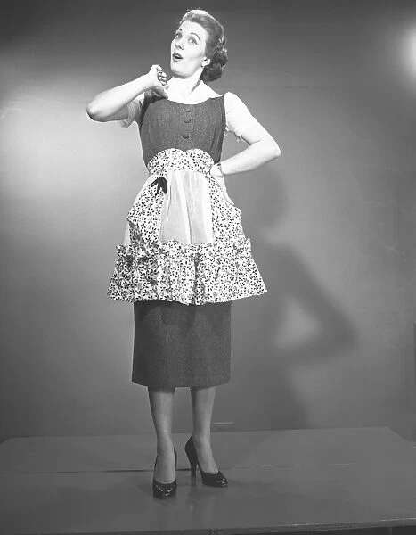 Woman in apron posing in studio, (B&W), , portrait