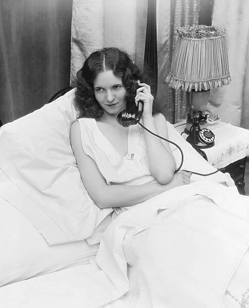Woman sitting in bed, talking on phone