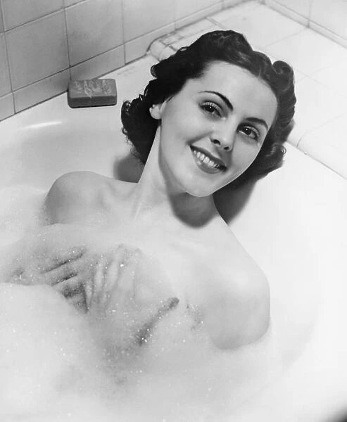 Woman taking bath in bathtub (B&W), portrait
