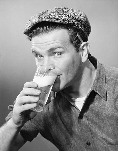 Workman in cap drinking beer in studio, (B&W), (Close-up), (Portrait)