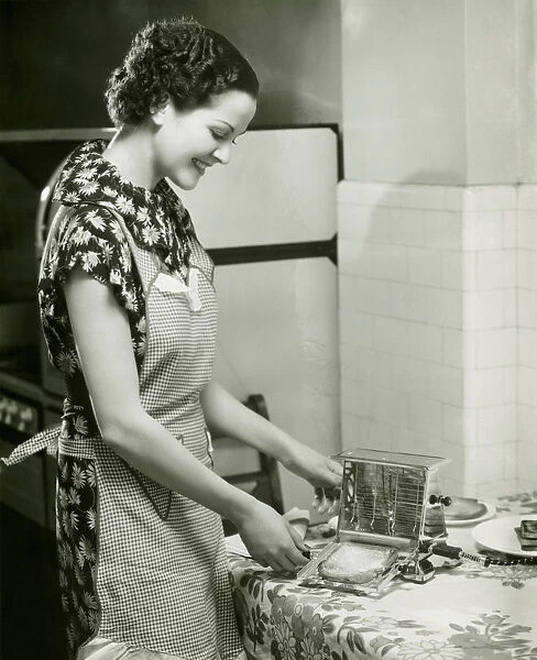 Young woman making slice of toast, (B&W), portrait