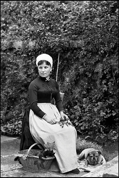 Portrait of a servant holding a branch, with dog and basket. At the Abbey of Septfontaines, Bourmont (Haute Marne). Photograph, circa 1870-1886, by Paul Emile Theodore Ducos (1849-1913)