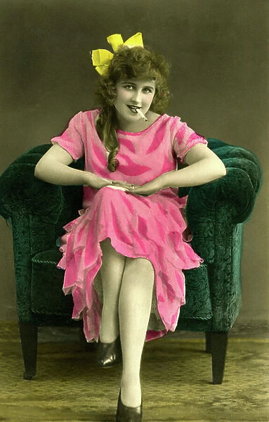 Portrait of woman in pink dress with cigarette in mouth; photograph circa 1915