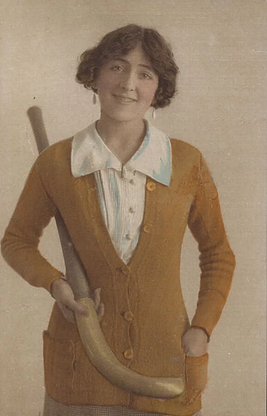 Pretty girl, in knitted jumper, with pearl earrings, holding hockey stick (photo)