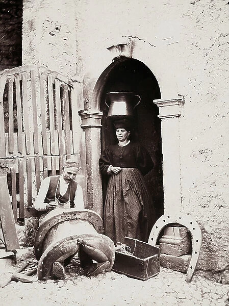 Saddle maker in front of his house, next to woman in traditional costume, 1910 (print on double-weight paper)