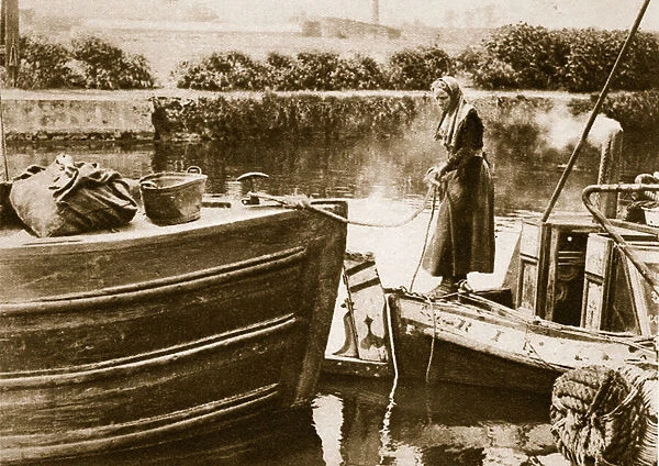 A woman securing the stern of her barge, London (sepia photo)