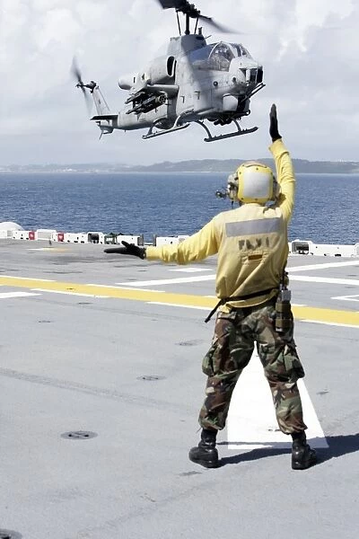 Airman directs an AH-1W Super Cobra onto the flight deck of USS Essex