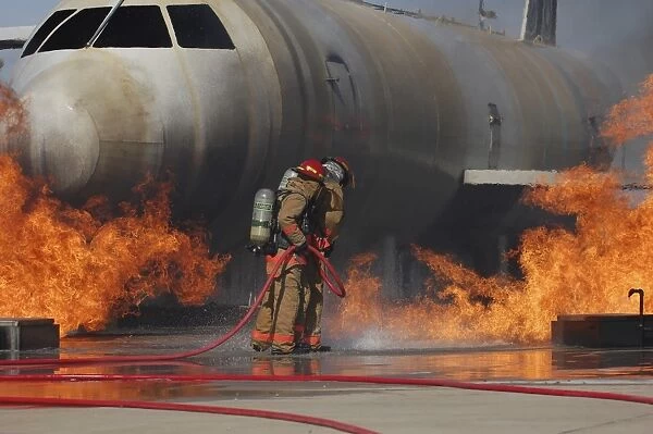 Airmen extinguish a fire on a training module to demonstrate an aircraft incident