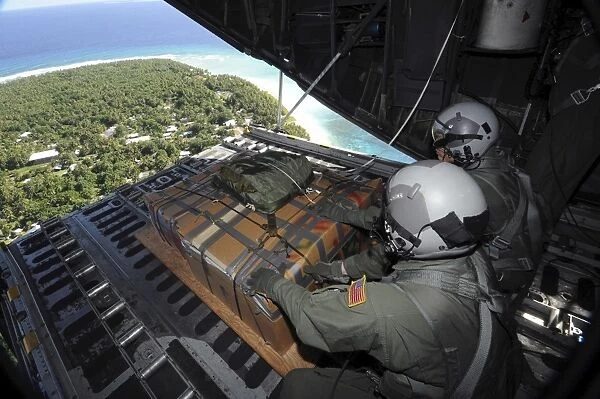 Airmen push out a pallet of donated goods over the Island of Yap from a C-130 Hercules