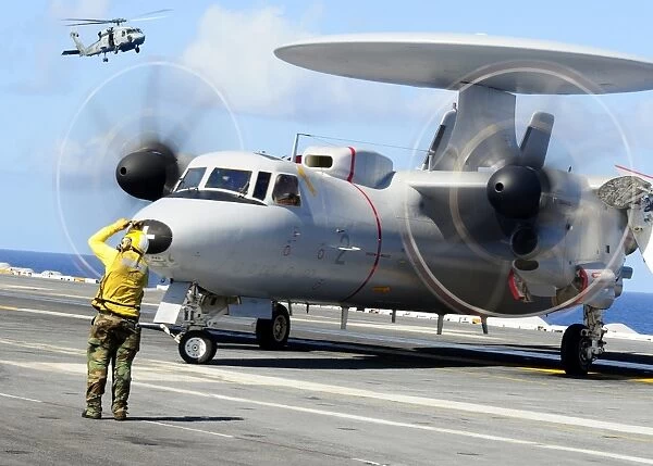 An Aviation Boatswains Mate directs a French E-2C Hawkeye abord USS Theodore Roosevelt