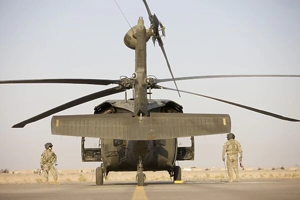 Crew Chiefs stand beside their UH-60L Black Hawk helicopter