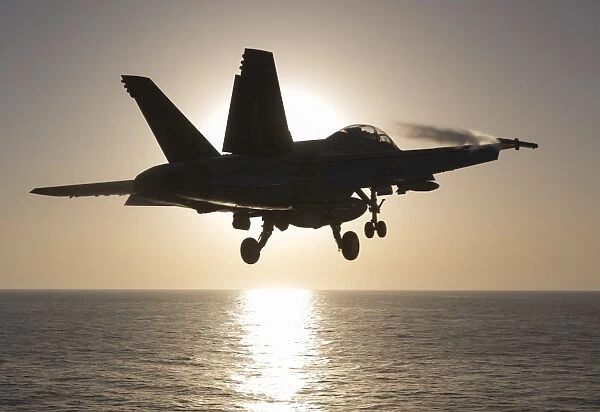 An F  /  A-18F Super Hornet takes off into the morning Sun over the Arabian Sea